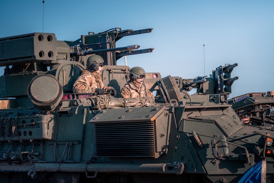 Two soldiers look out from a large military vehicle.