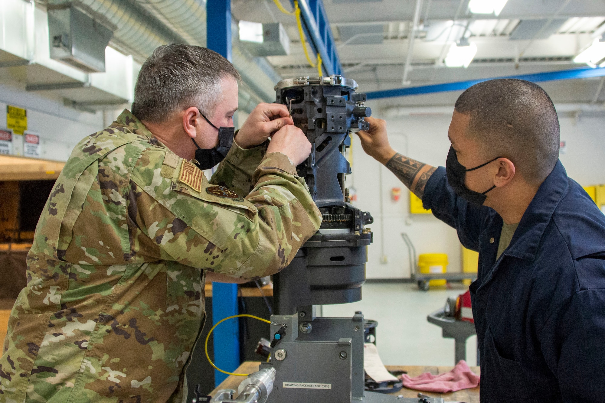 Senior Master Sgt. Ryan Zepp and Tech. Sgt. Matias Castro disassemble a M61A2 Gatling gun.