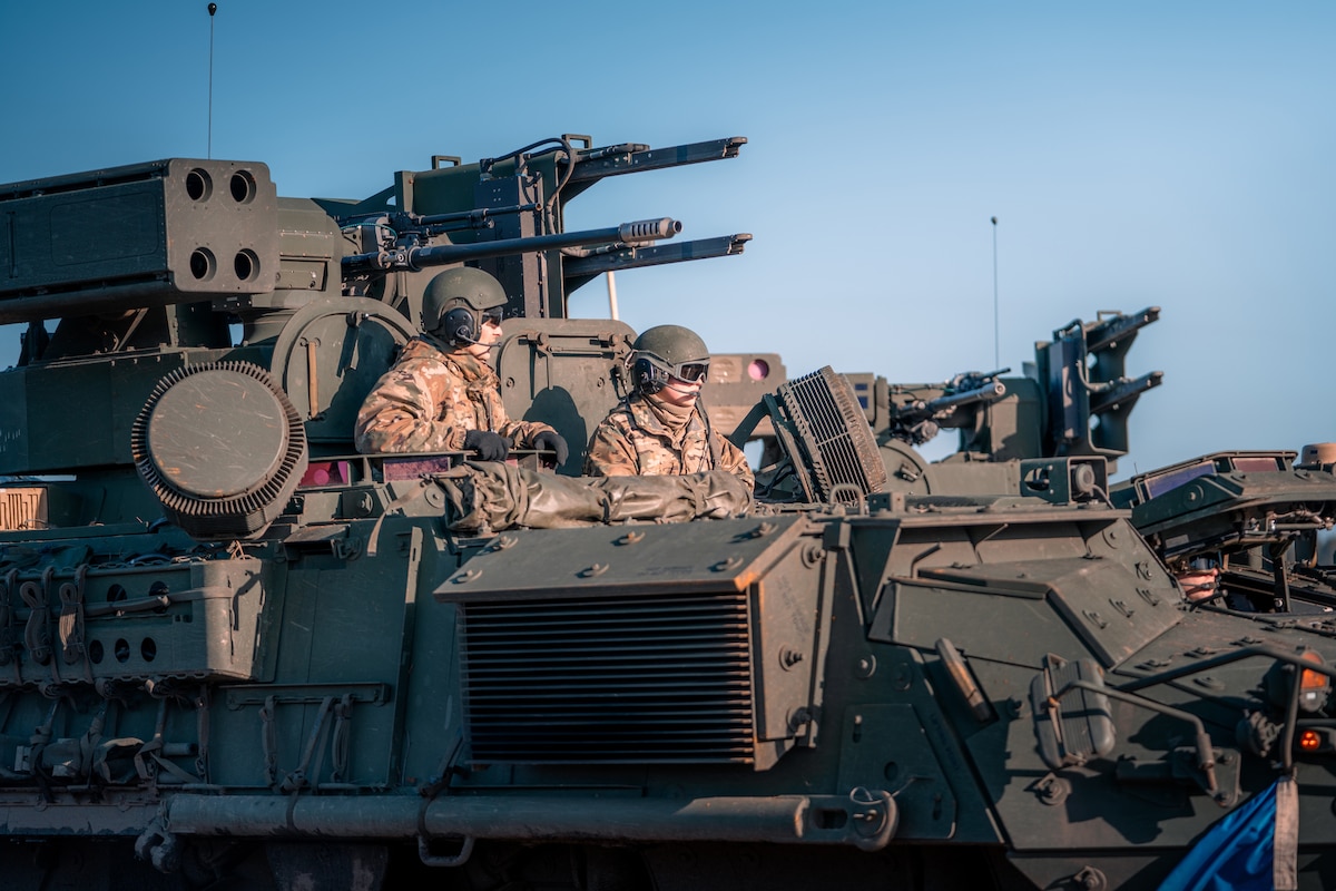 Two soldiers look out from a large military vehicle.