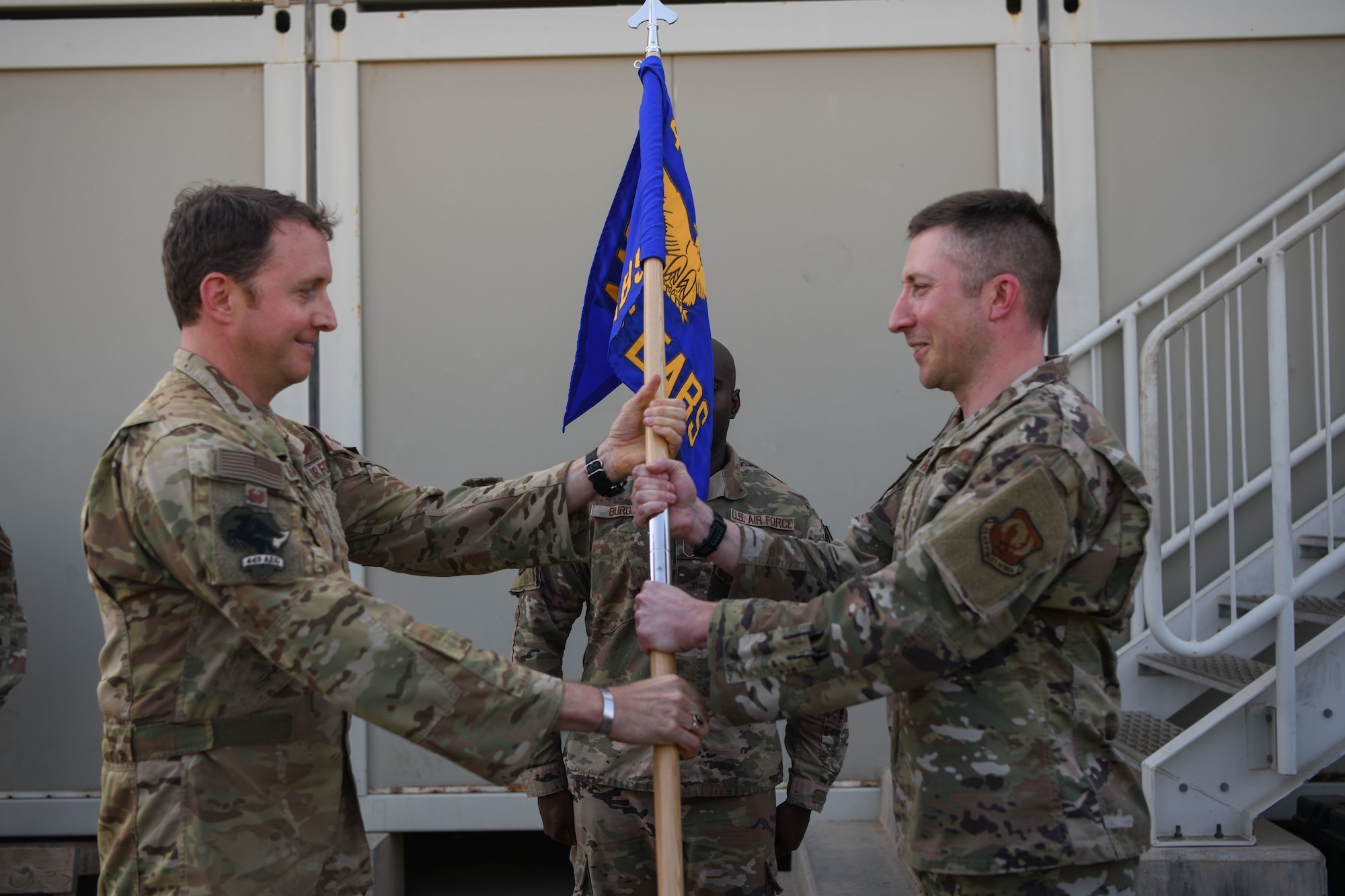 U.S. Air Force Col. Matthew A. Bartlett, 449th Air Expeditionary Group commander, right, passes the guideon to U.S. Air Force Maj. Joshua Hager, 726th Expeditionary Air Base Squadron incoming commander during a change of command at Camp Lemonnier, Djibouti, Feb. 11, 2022. The 726th EABS provides proactive support for civil engineering, logistics, communications contracting, radar systems and munitions management enabling secure, reliable, flexible air power projection platforms in support of the Combined Joint Task Force - Horn of Africa and combatant commanders (U.S. Air Force photo by Senior Airman Ericka A. Woolever)