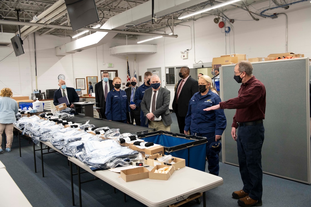 uniformed and civilian men and women look at uniform items on table