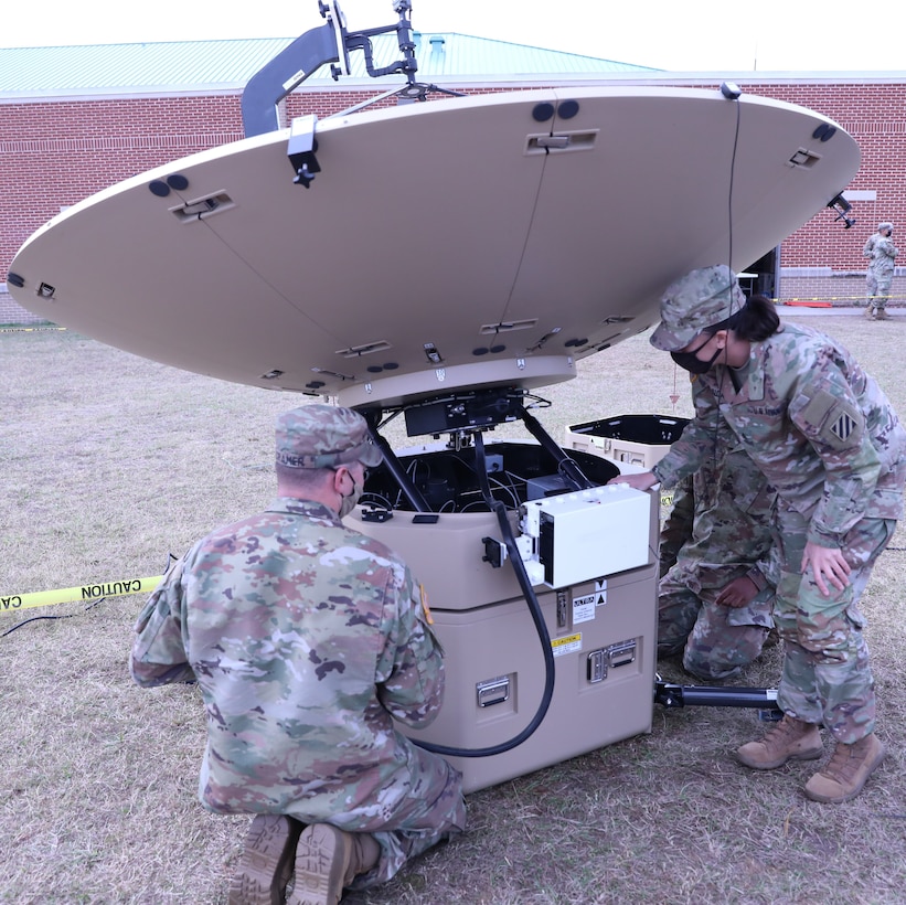 Soldiers work on satellite gear.
