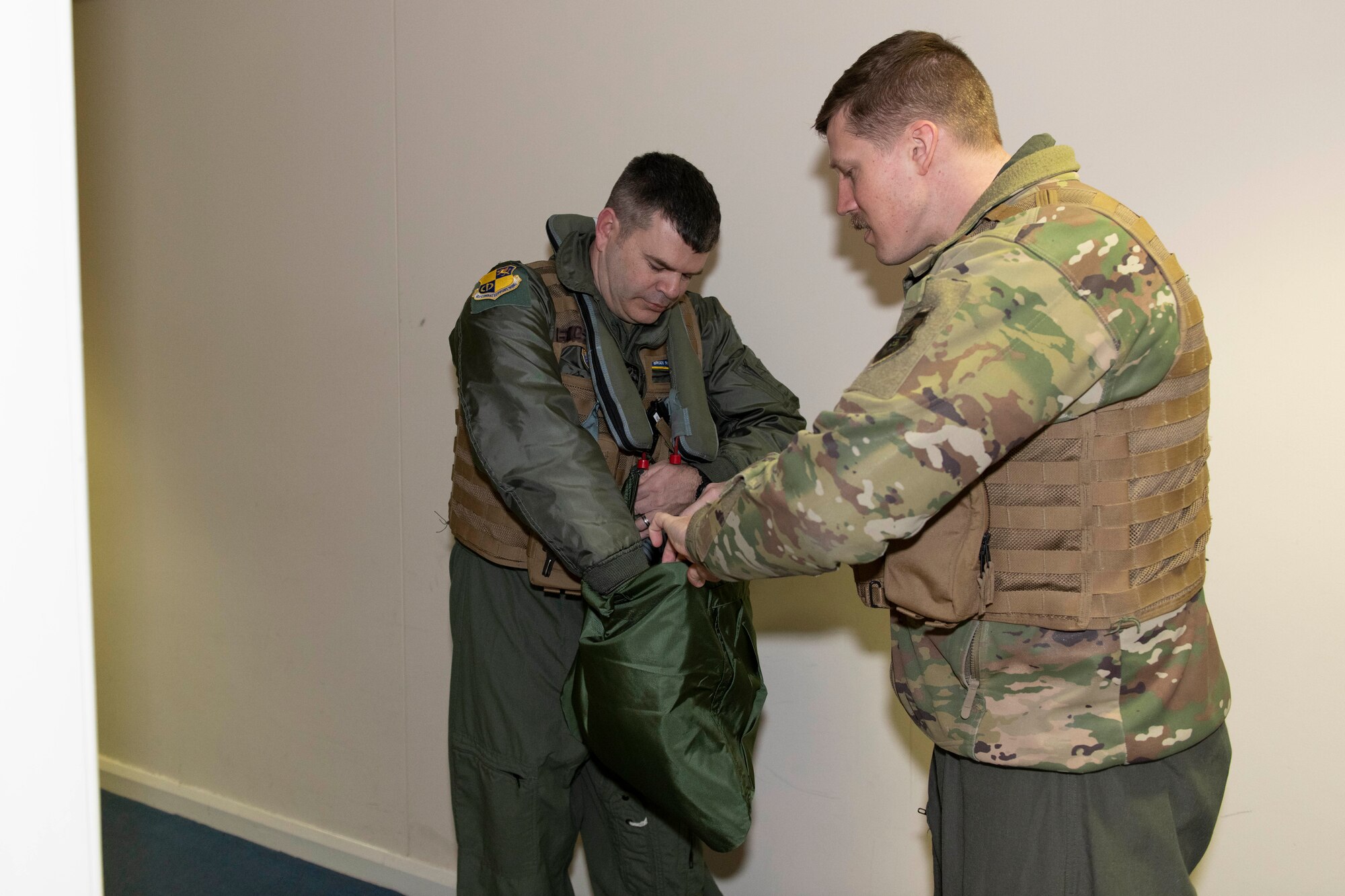 A U.S. Air Force B-52H Stratofortress pilot, right, assigned to the 69th Expeditionary Bomb Squadron, assists Col. Brian Filler, left, 501st Combat Support Wing commander, with flight gear at RAF Fairford, England, Feb. 22, 2022. Filler completed several pre-flight requirements prior to boarding a B-52H Stratofortress for a familiarization flight. (U.S. Air Force photo by Senior Airman Jennifer Zima)