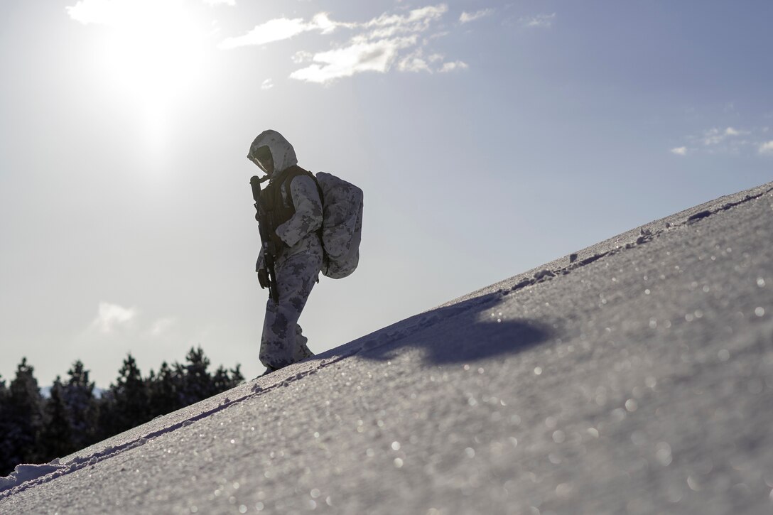 A Marine wearing cold weather gear descends an icy slope.