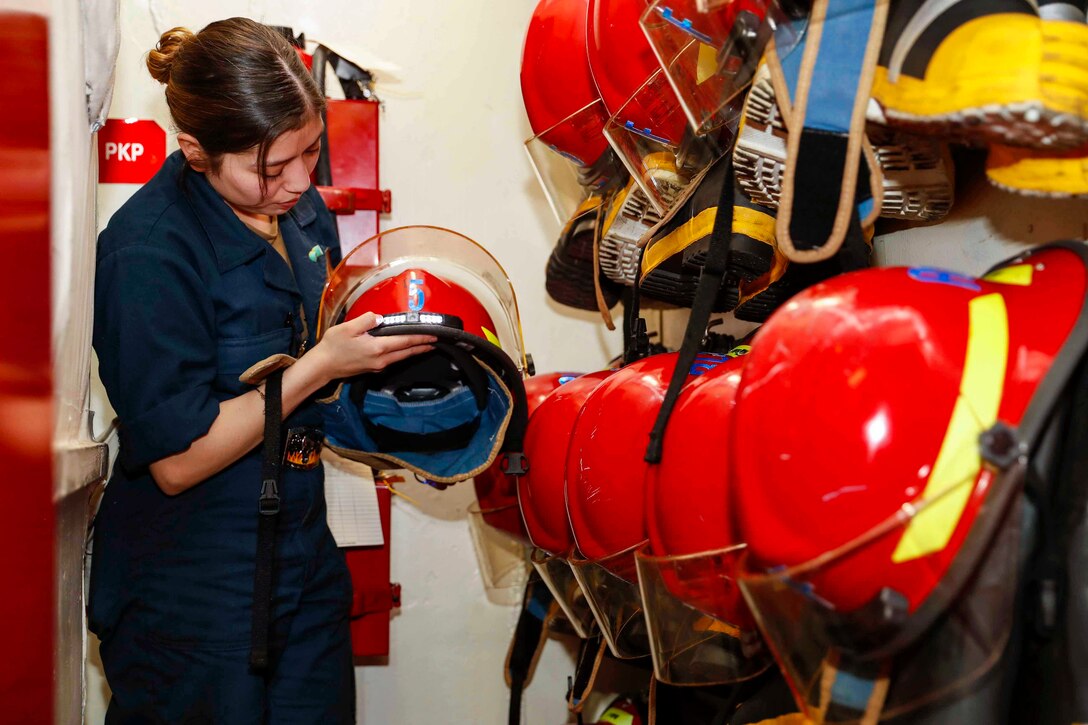 A sailor looks at a firefighter helmet.