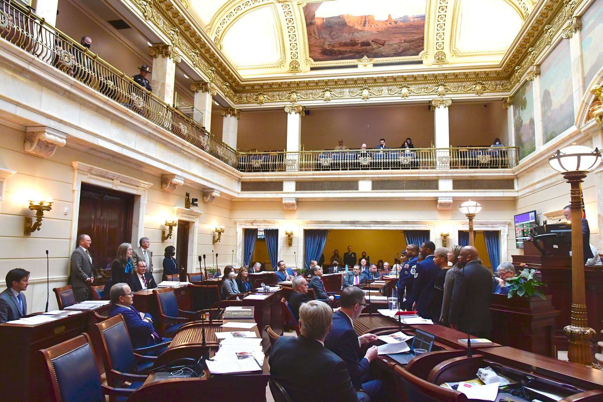 Military and civilian families stand in front of legislators inside the chamber.