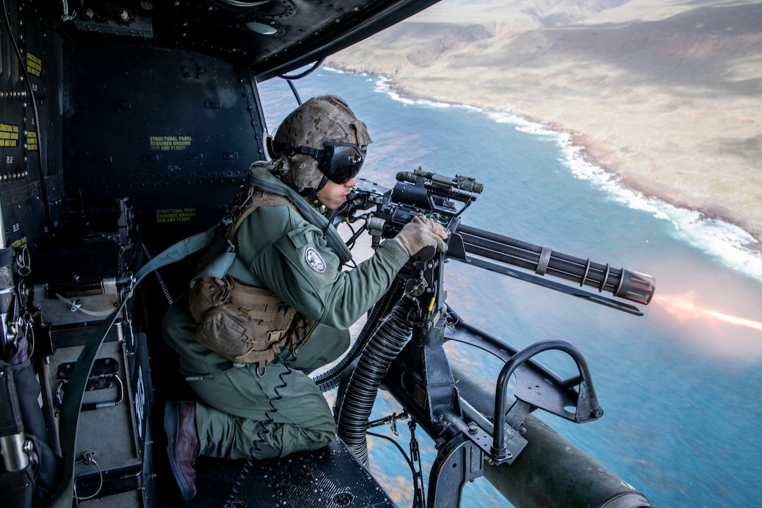 A Marine fires a gun from a helicopter.