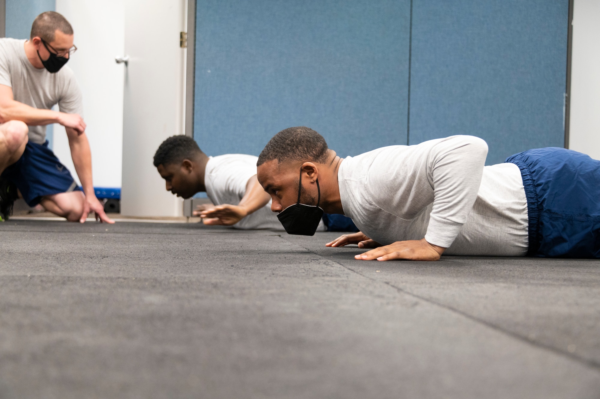 One person kneels, while two others perform push-up movements.