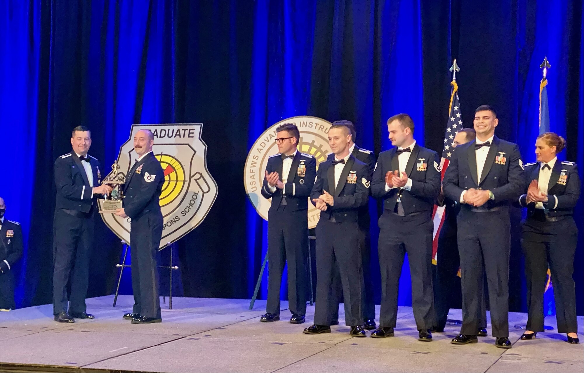 People in Air Force Dress Mess stand on stage.