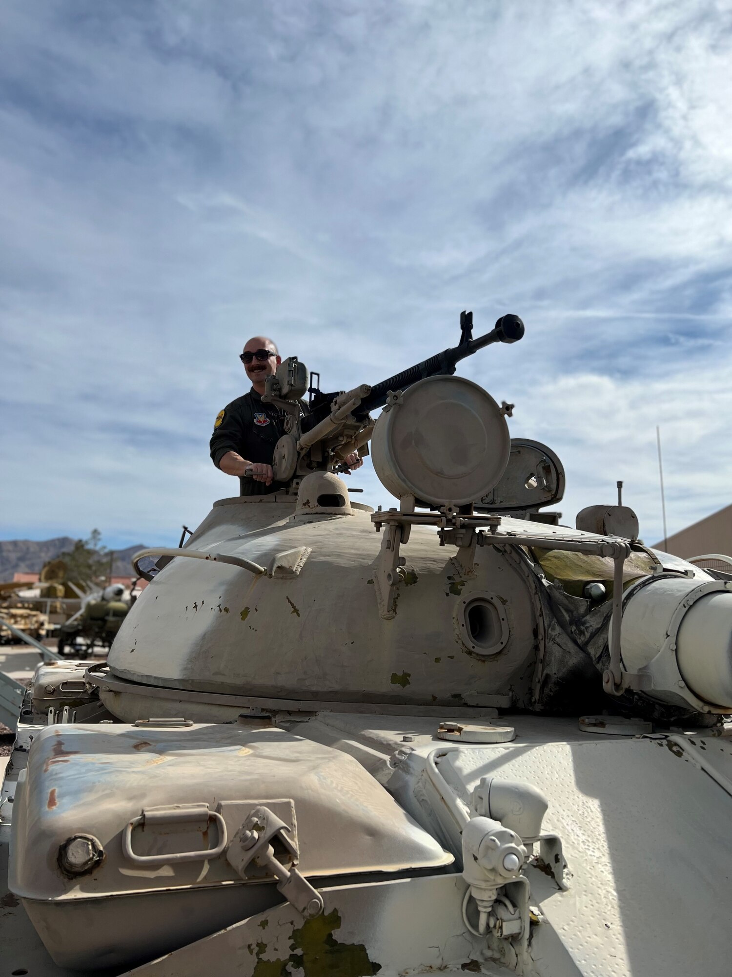 A man in a flight suit stands on a tank.