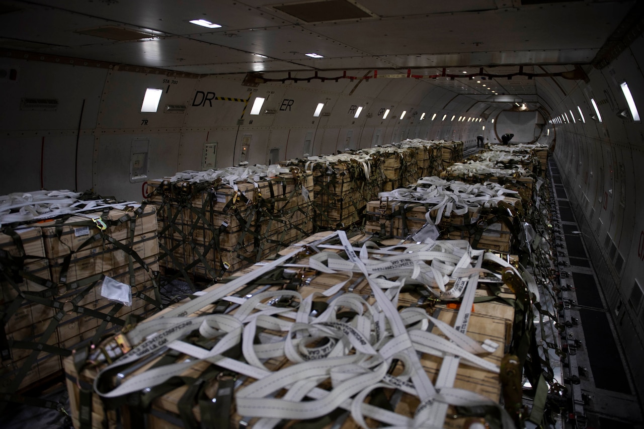 More than a dozen pallets of cargo are tied down with netting inside the cargo hold of an aircraft.