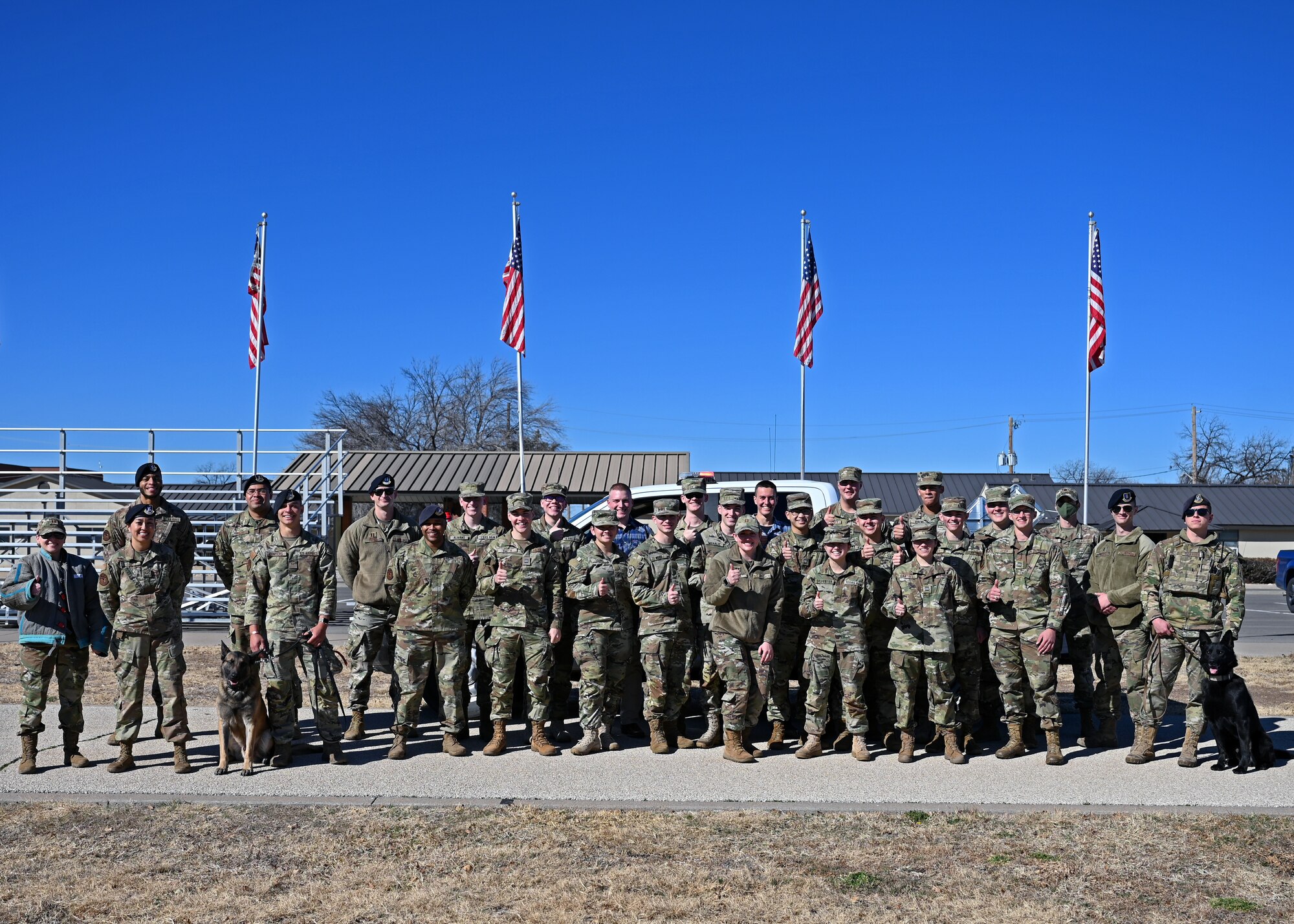 Texas A&M University cadets pose in front of a patrol vehicle with 17th Security Forces Defenders at the Goodfellow Air Force Base, Texas, parade field Feb. 18, 2022. Defenders provided a military working dog demonstration and led a discussion with the cadets on how handlers work together with their dogs to protect the base.  (U.S. Air Force photo by Senior Airman Ethan Sherwood)
