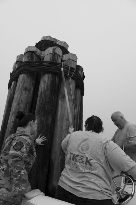 U.S. Air Force Tech. Sgt. Monica Wright, 1st Special Operations Logistics Readiness Squadron fuels quality compliance section chief, and members of TK&K Services grab on to a wooden pillar during a spill prevention and response exercise Feb. 24, 2022, at Hurlburt Field, Florida.
