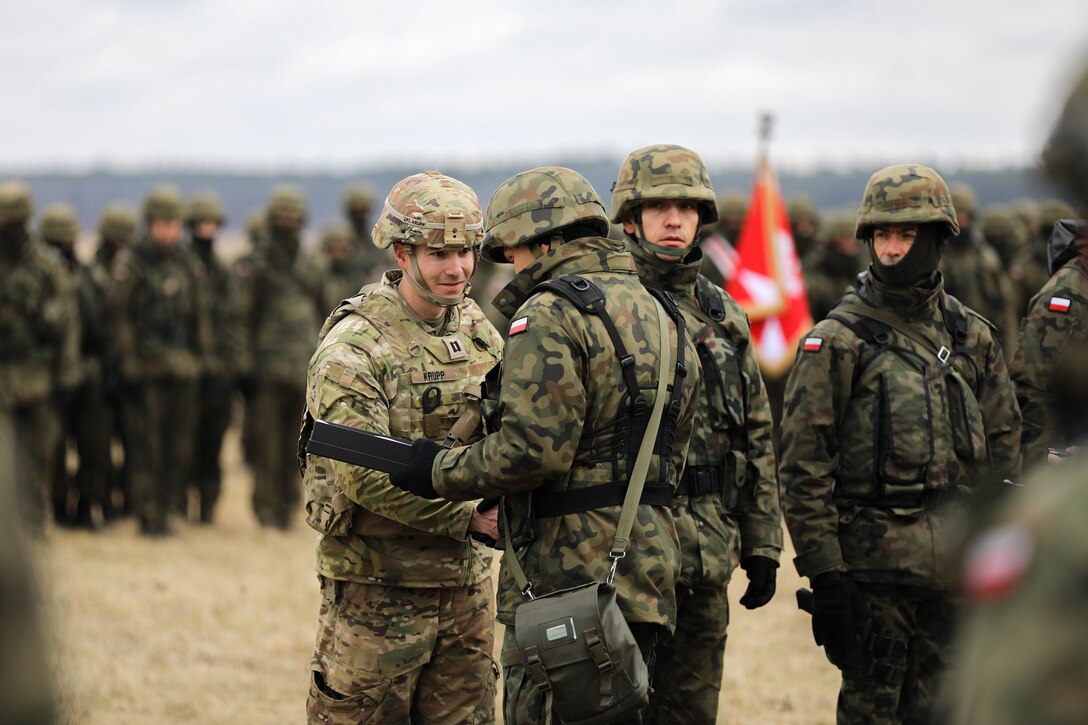 A soldier receives an award from another soldier.