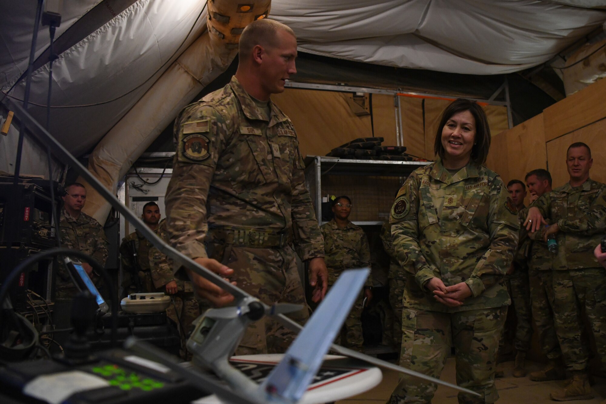 Senior Airman Tyler Sipe, 409th Expeditionary Security Forces Squadron small unmanned aircraft system operators, briefs Chief Master Sgt. of the Air Force JoAnne S. Bass about the RQ-11B Raven, a small hand-launched remote controlled unmanned aerial vehicle, at Nigerien Air Base 201, Agadez, Dec. 20, 2021. The 409th Air Expeditionary Group supports intelligence, surveillance, and reconnaissance (ISR) capabilities, aircraft launch and recovery elements and base operating support integrator (BOS-I) capabilities for U.S. forces in Niger while working closely with and enabling their Nigerien Armed Forces counterparts. (U.S. Air Force photo by Senior Airman Ericka A. Woolever)