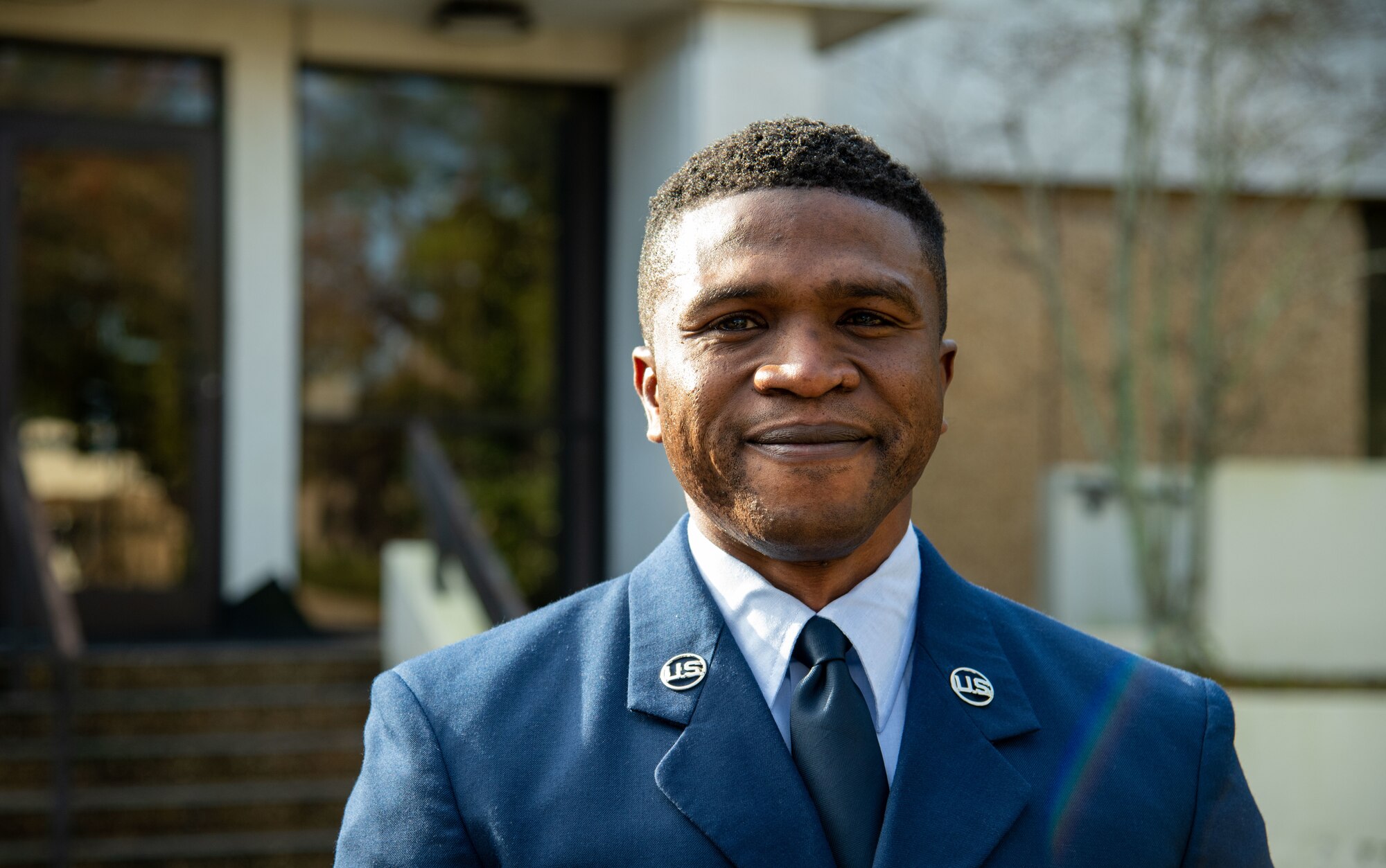 Bust shot of Airman in service blues outside of a building