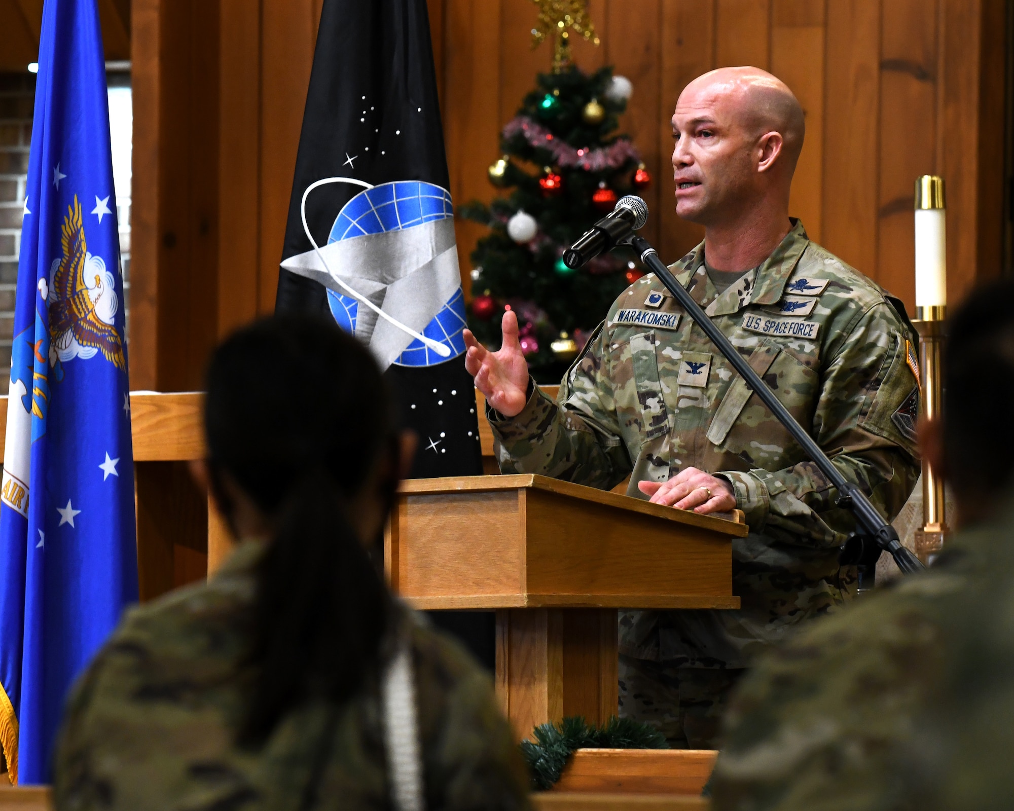 A man stands at a podium giving a speech to many Airmen