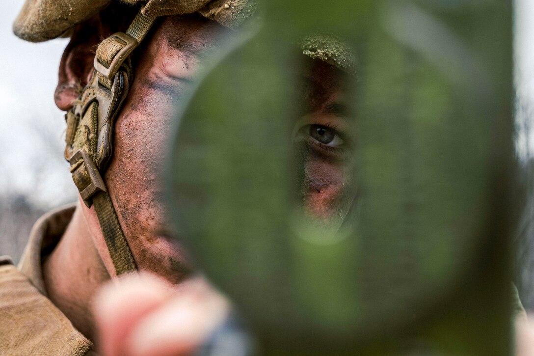 A green compass obscures a Marine's face except for an eye as he holds it up.