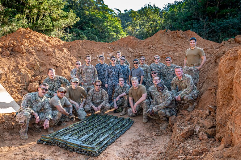Group photo of U.S. service members and Japan Air  Self-Defense Force members gathered around an arrangement of explosives.