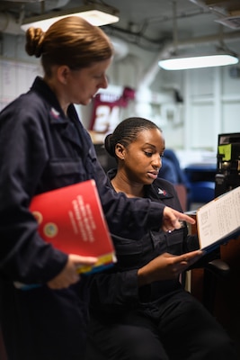 171205-N-MJ135-1006 ARABIAN GULF (Dec. 5, 2017) Legalman 2nd Class Diandra Johnson and Legalman 1st Class Amber Ambrozich reviews a case file aboard the aircraft carrier USS Theodore Roosevelt (CVN 71). Theodore Roosevelt and its carrier strike group are deployed to the U.S. 5th Fleet area of operations in support of maritime security operations to reassure allies and partners and preserve the freedom of navigation and the free flow of commerce in the region. (U.S. Navy photo by Mass Communication Specialist 3rd Spencer Roberts/Released)