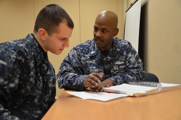 Legalman 1st Class Earl Brown, right, reviews legal paperwork with Seaman Recruit Joshua Robison. Brown was named the 2013 Naval Legal Service Command Sailor of the Year. Recruit Training Command Great Lakes trains more than 37,000 volunteer civilian recruits annually. (U.S. Navy photo by Lt. j.g. Adam Demeter/Released)