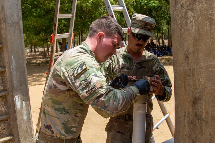 U.S. Army Sgt. 1st Class Shawn Danaher and Sgt. Quinton Banus, both with B Company, 572nd Brigade Engineer Battalion, Task Force Iron Gray, Combined Joint Task Force – Horn of Africa (CJTF-HOA), repair the gutter system at a school in Lamu County, Kenya, Nov. 2, 2021. CJTF-HOA’s efforts, as part of a comprehensive whole-of-government approach, are aimed at increasing African partner nations’ capacity to maintain a stable environment, with an effective government that provides a degree of economic and social advancement to its citizens.