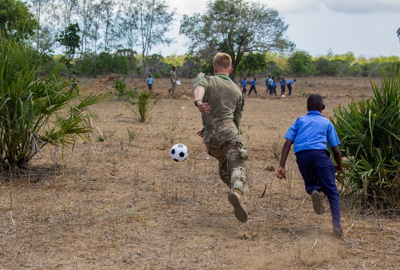 U.S. Army Spc. Tyler Hoar, C Company, 1-102nd Infantry Regiment (Mountain), Task Force Iron Gray, Combined Joint Task Force – Horn of Africa (CJTF-HOA), plays soccer with a student during a cultural engagement at a school in Lamu County, Kenya, Nov. 2, 2021. CJTF-HOA efforts, as part of a comprehensive whole-of-government approach, are aimed at increasing African partner nations’ capacity to maintain a stable environment, with an effective government that provides a degree of economic and social advancement to its citizens.