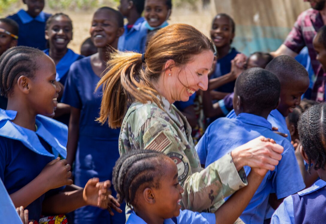 U.S. Air Force Maj. Kathryn Escatel with the 475th Expeditionary Air Base Squadron, dances with students during a cultural engagement at a school in Lamu County, Kenya, Nov. 2, 2021. The Combined Joint Task Force – Horn of Africa’s efforts, as part of a comprehensive whole-of-government approach, are aimed at increasing African partner nations’ capacity to maintain a stable environment, with an effective government that provides a degree of economic and social advancement to its citizens.