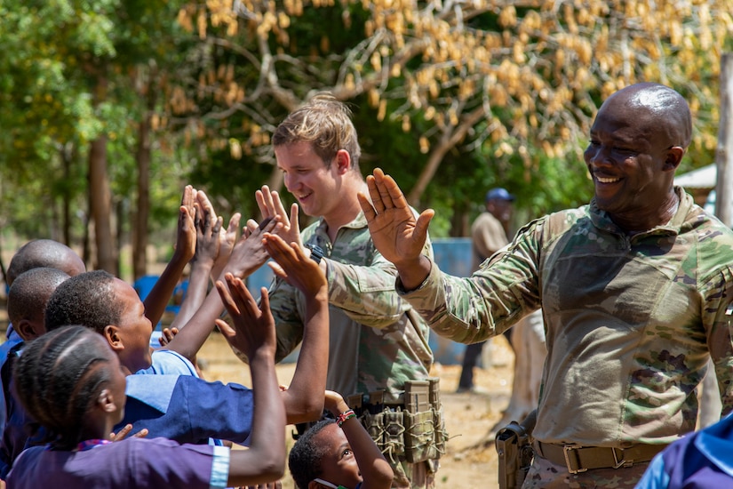 U.S. Army Sgt. Connor Dowd and Sgt. 1st Class Gregory Reid with C Company, 1-102nd Infantry Regiment (Mountain), Task Force Iron Gray, Combined Joint Task Force – Horn of Africa (CJTF-HOA), high-five students during a cultural engagement at a school in Lamu County, Kenya, Nov. 2, 2021. CJTF-HOA’s efforts, as part of a comprehensive whole-of-government approach, are aimed at increasing African partner nations’ capacity to maintain a stable environment, with an effective government that provides a degree of economic and social advancement to its citizens.