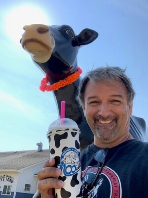 Man standing in front of cow statue with drink