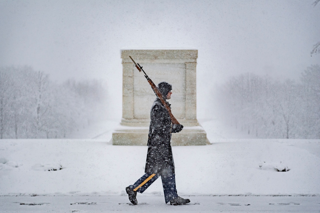 A soldier walks in the snow at the Tomb of the Unknown Soldier.