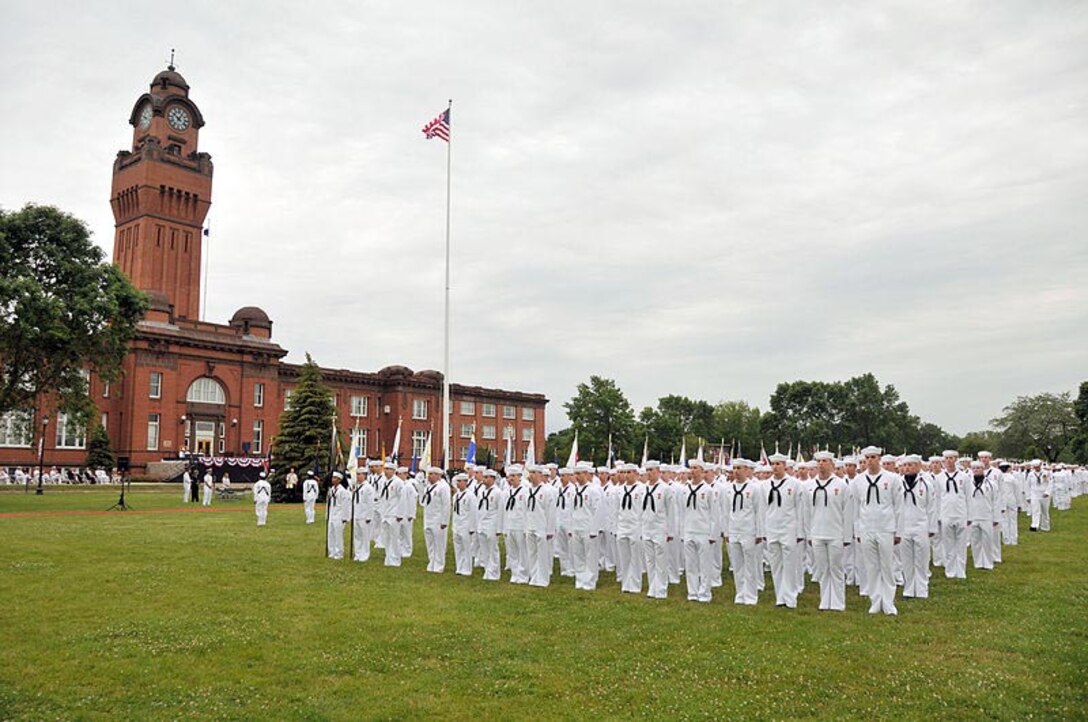 Enlisted sailors stand in formation in their service dress whites.