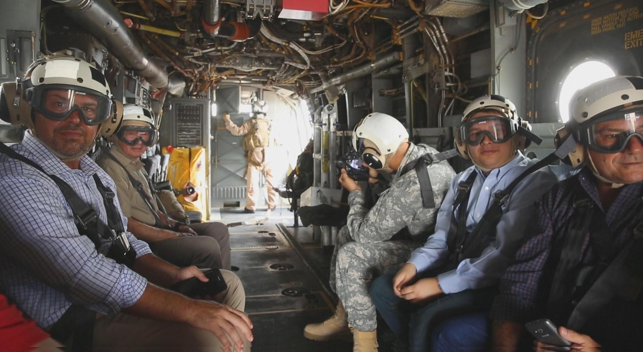 People in helmets and goggles sit strapped to helicopter seats.