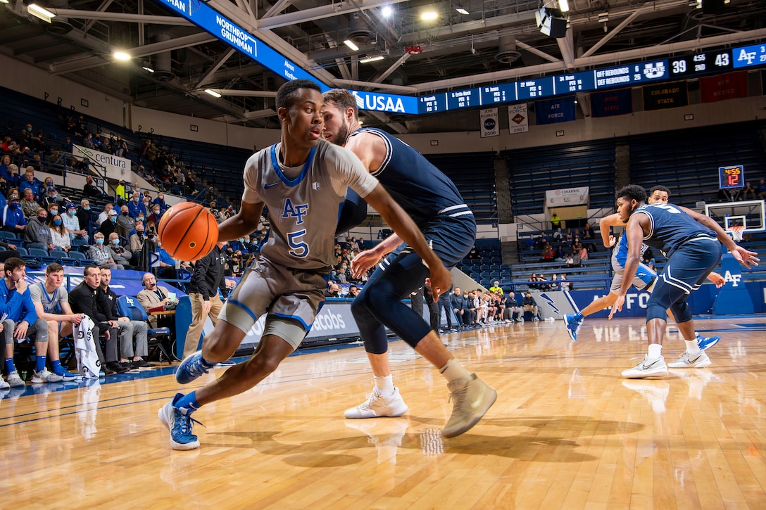 A basketball player dribbles the ball as he drives to the basket.