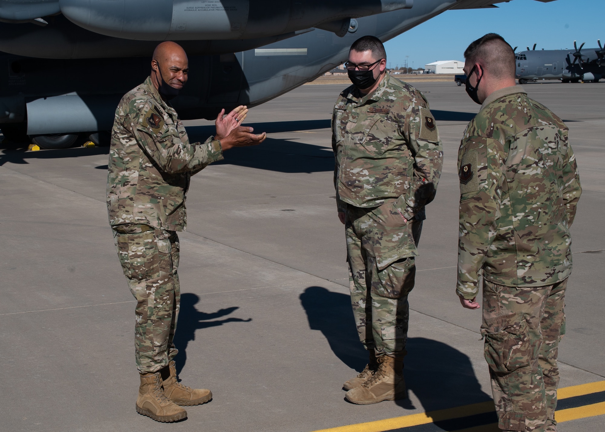 An Air Force Colonel lauds an Airmen in front of a military cargo aircraft.