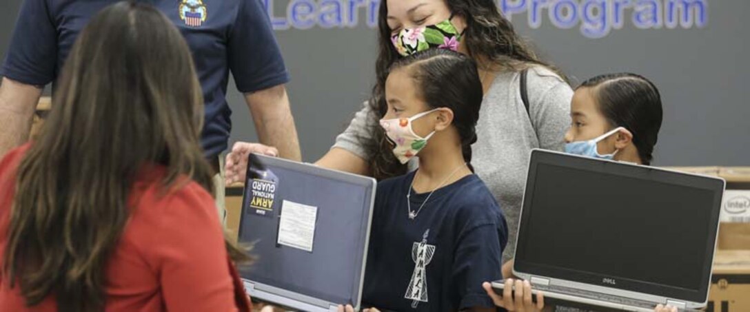 Students in Guam investigate new laptop computers.