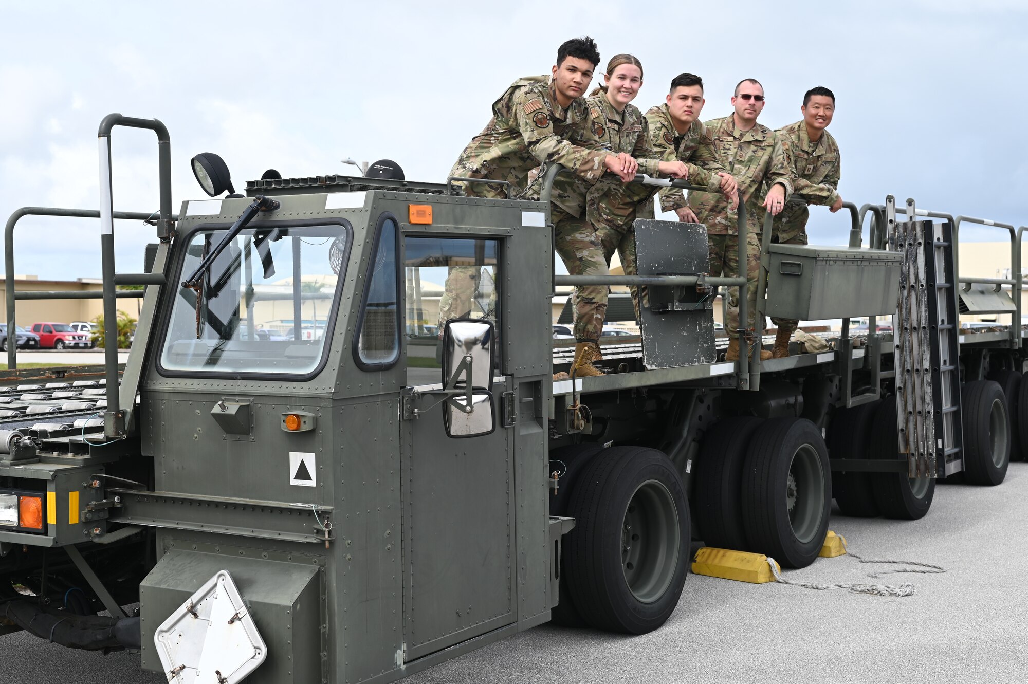 Airmen from the 36th Logistics Readiness Squadron pose on a container loader for a group picture at Andersen Air Force Base, December 15th, 2021. The Airmen formed a last minute cargo load team in support of an emergency delivery of Reverse Osmosis Water Purification Units to Wake Island after their water purifier malfunctioned, leaving the atoll without potable water. (U.S. Air Force photo by Staff Sgt. Nicholas Crisp)