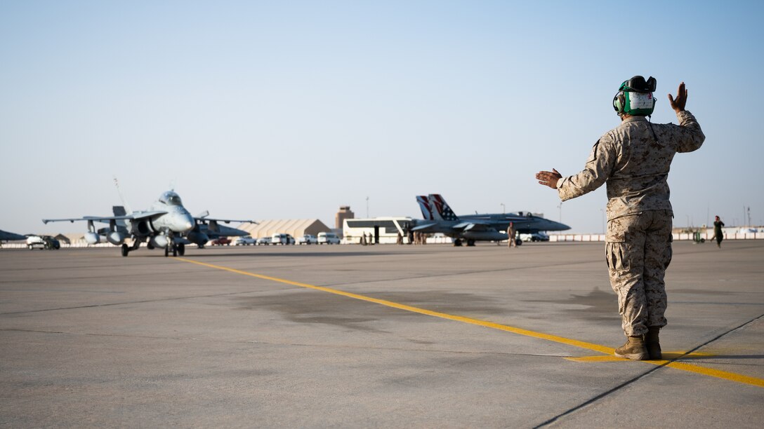 A U.S. Marine from the Marine Fighter Attack Squadron marshals in an F/A-18 Hornet at Prince Sultan Air Base, Kingdom of Saudi Arabia, Dec. 23, 2021. The VMFA-115 deployed a squadron of F/A-18s along with necessary support personnel in order to signal U.S. and coalition resolve in the region. (U.S. Air Force photo by Senior Airman Jacob B. Wrightsman)