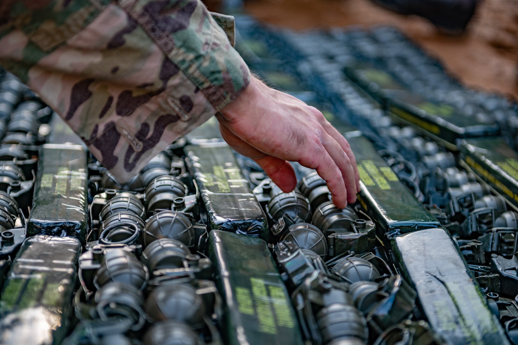 Explosive ordnance disposal technician sets down a grenade for disposal.
