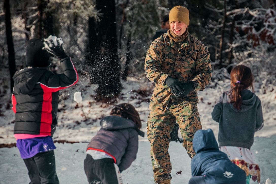 A soldier has a snowball fight with Afghan children.