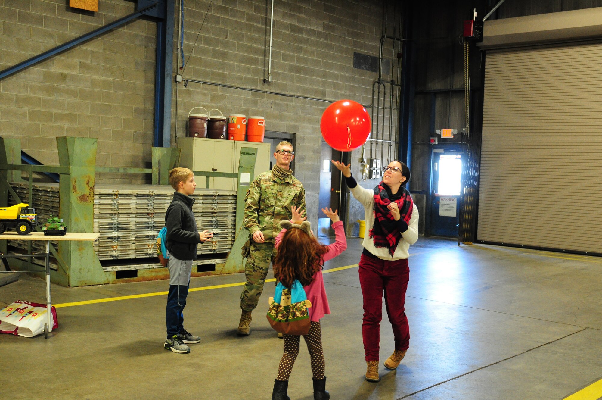 Senior Airman Daniel Schnaars, 87th Aerial Port Squadron, his wife, Davina and their children, play with a balloon during a family pre-deployment event inside the 87 APS warehouse at Wright-Patterson Air Force Base, Ohio, Nov. 7, 2021. During the event, families had the opportunity to connect to base and squadron resources, develop resiliency skills, and also learn more about the job their loved one will perform while deployed.