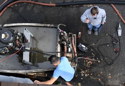IMAGE: Nhan Bui, statistician at Naval Surface Warfare Center Dahlgren Division, and Thomas Salvato, scientist, work on a boat motor. Using high powered microwave technologies, the pair are testing vessel stopping efforts.