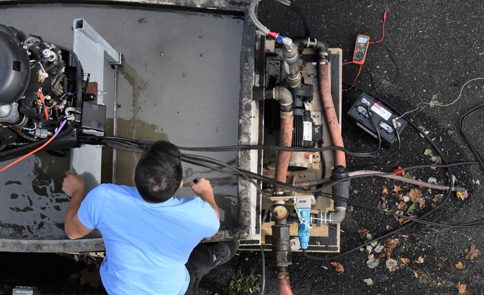 IMAGE: Nhan Bui, statistician at Naval Surface Warfare Center Dahlgren Division, works on a boat motor. Using high powered microwave technologies, the pair are testing vessel stopping efforts.