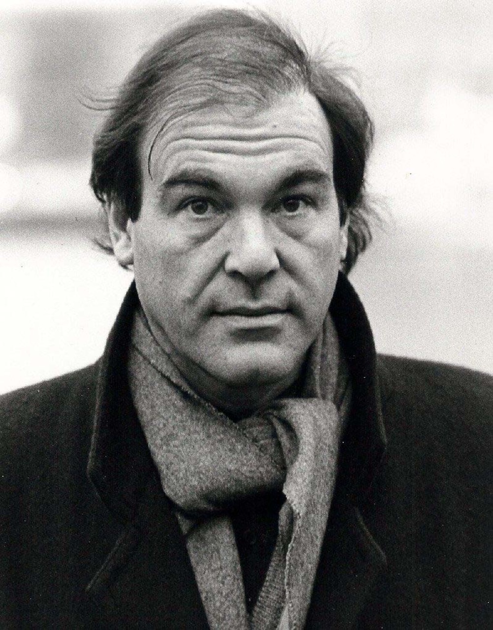 A man in a scarf poses for a photo.