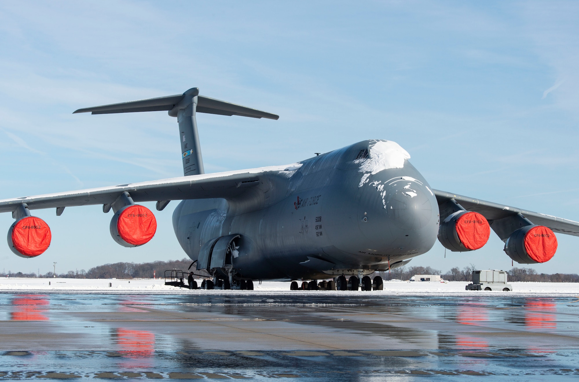 A snow-covered C-5M Super Galaxy sits on the flight line at Dover Air Force Base, Delaware, Jan. 4, 2022. Winter Storm Frida dropped eight inches of snow on the base, initiating the first snow removal operations of the year. (U.S. Air Force photo by Roland Balik)
