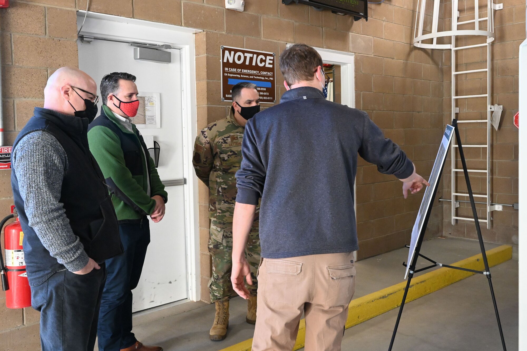 Three men watch another man point to a chart.