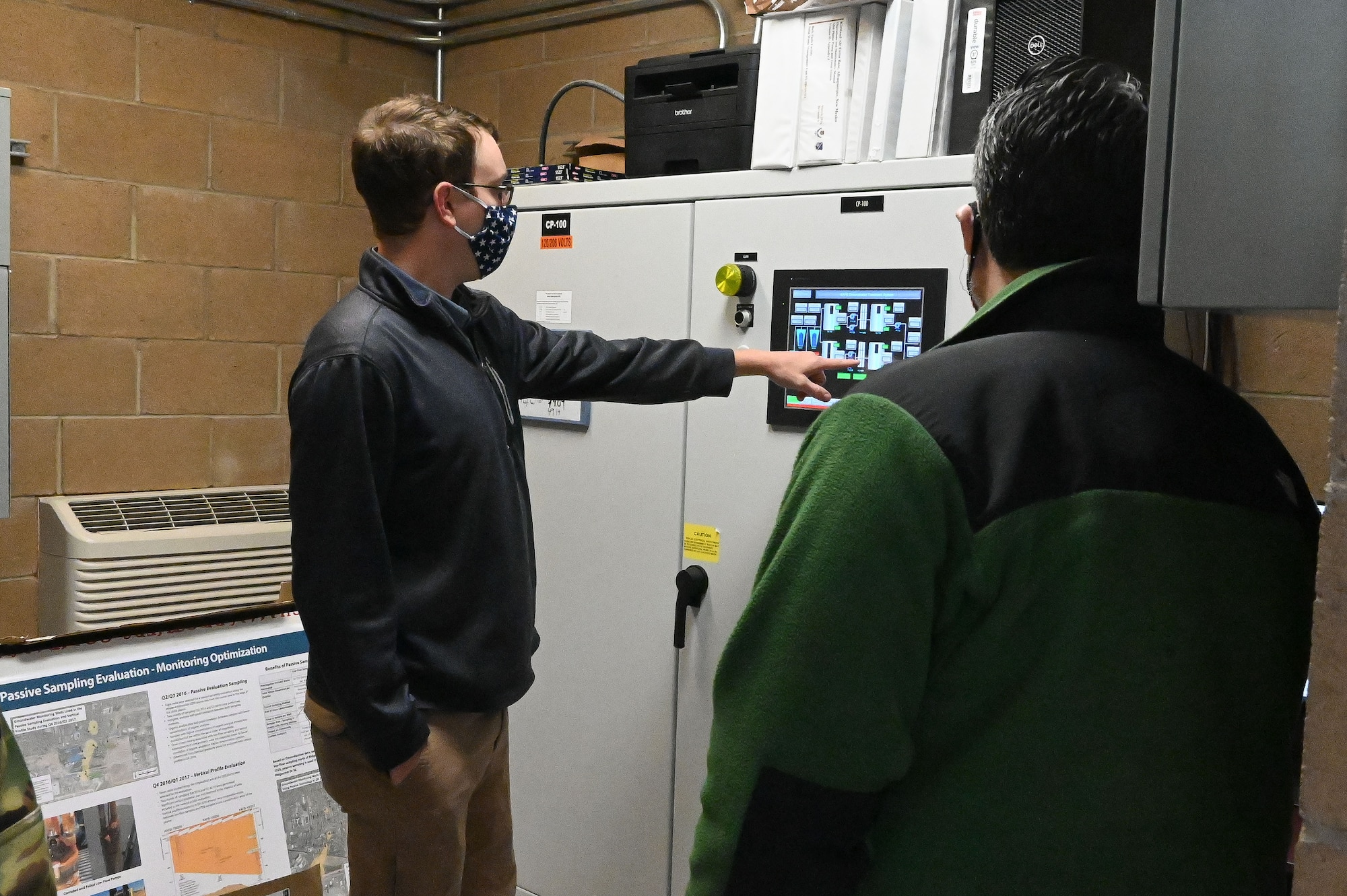 A man points at a screen while another man watches.