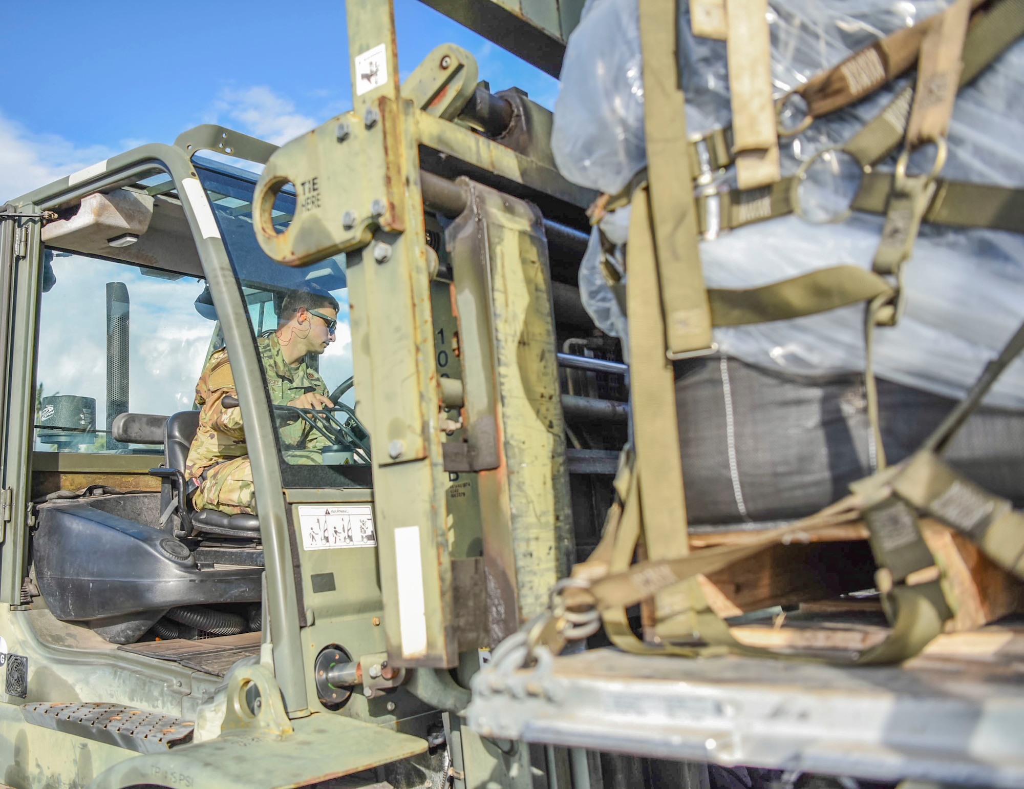 U.S. Air Force Senior Airman Chris Capra-Gerske, 647th Logistics Readiness Squadron combat mobility flight team member, downloads cargo within the cargo deployment function yard at Joint Base Pearl Harbor-Hickam, Hawaii, Dec. 22, 2021. The cargo was delivered by a C-5 Super Galaxy from Travis Air Force Base, carrying equipment to support the Granular Activated Carbon water filtration system and the water recovery efforts on Oahu.  (U.S. Air Force photo by Tech. Sgt. Anthony Nelson Jr.)