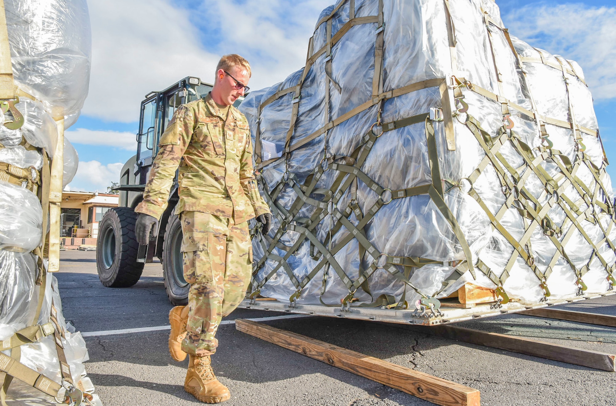 U.S. Air Force Staff Sgt. Austin Chambers, 647th Logistics Readiness Squadron NCOIC of air transportation function spots the forklift driver while properly placing dunnage within the cargo deployment function yard at Joint Base Pearl Harbor-Hickam, Hawaii, Dec. 22, 2021. The cargo was delivered by a C-5 Super Galaxy from Travis Air Force Base, carrying equipment to support the Granular Activated Carbon water filtration system and the water recovery efforts on Oahu.  (U.S. Air Force photo by Tech. Sgt. Anthony Nelson Jr.)