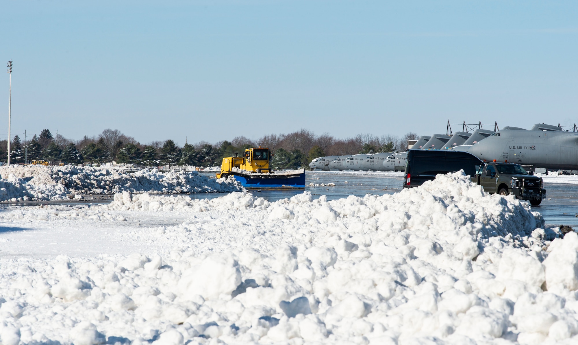 A 436th Civil Engineer Squadron member plows snow on the flight line at Dover Air Force Base, Delaware, Jan. 4, 2022. Snow removal crews worked around the clock to remove eight inches of snow and ice from Winter Storm Frida that accumulated on the two runways and numerous taxiways. (U.S. Air Force photo by Roland Balik)